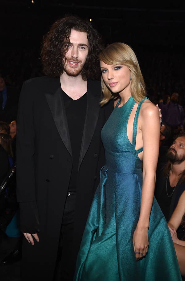 Two people at an event. Person on the left in a black suit. Person on the right in a shimmering gown with cut-out details