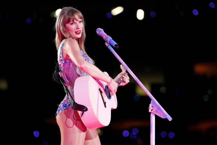 A musician performs on stage with a guitar, wearing a sparkly outfit