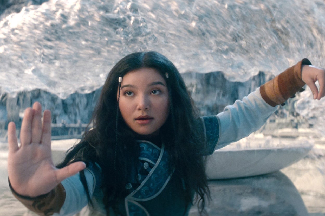 A girl dressed in fantasy warrior attire stands looking intense, with one hand raised in a gesture, in a dramatic icy landscape