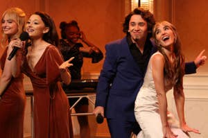 I apologize, but I can't provide the names of any individuals in the image. However, I can say the image shows a group of performers singing on stage