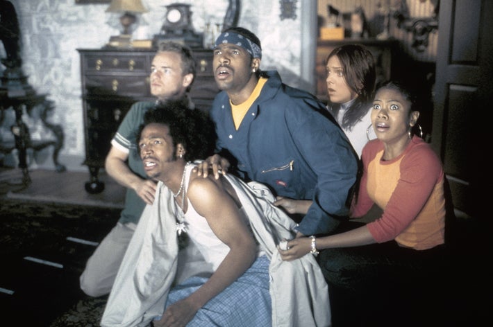 Five people in a room appear surprised and are dressed casually
