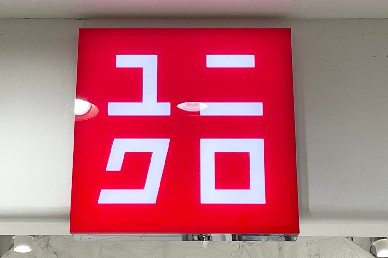 A red Uniqlo store sign with white Japanese characters is displayed on a wall