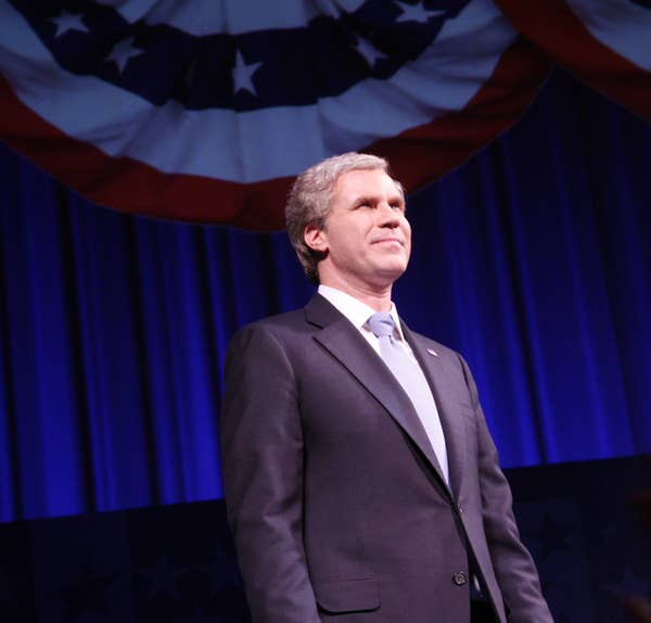 Will in a suit and wig stands on stage with star-patterned banners above