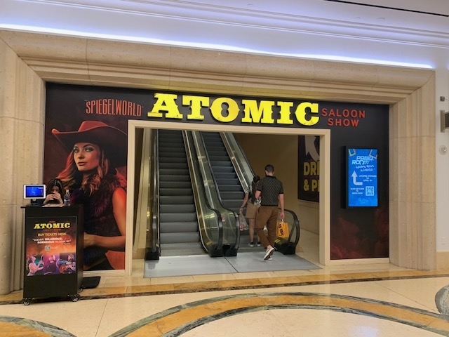 Entrance to Atomic Saloon Show at Spiegelworld with two people approaching escalators