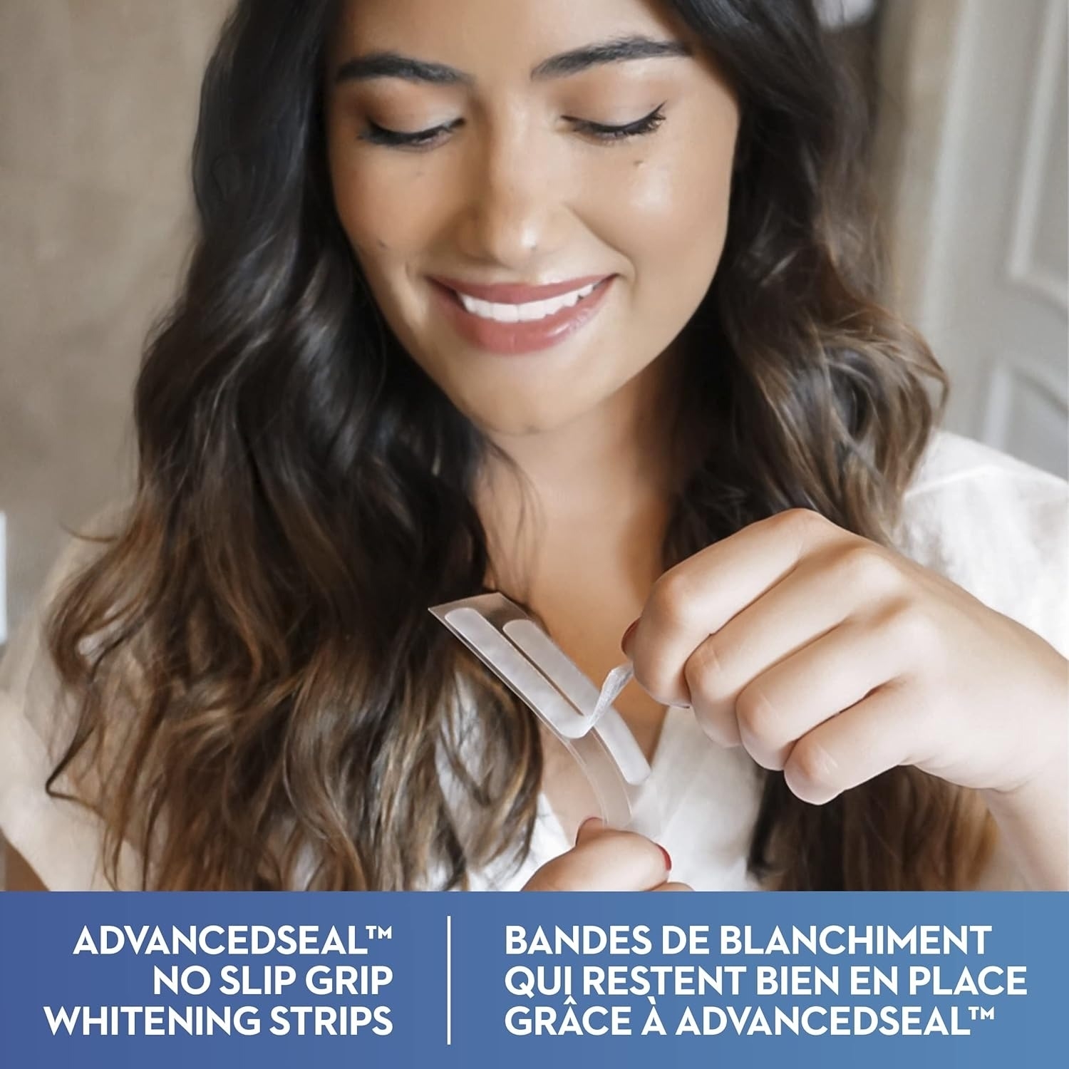 Adult holding teeth whitening strips, smiling. Text: Advancedseal™ no slip grip whitening strips; bandes de blanchiment qui restent bien en place grâce à Advancedseal™