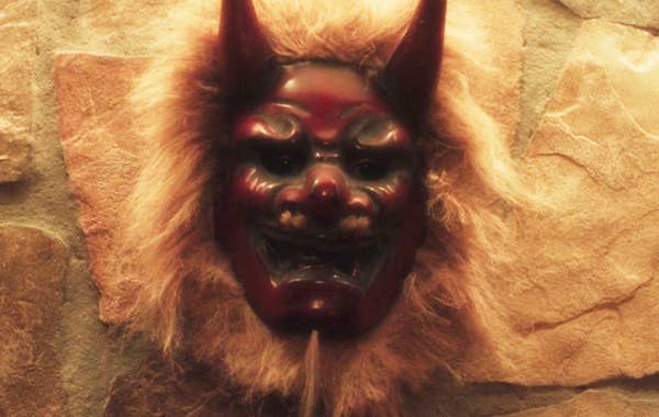 Decorative mask with horns and fur, resembling a demon or mythical creature, mounted on a stone wall