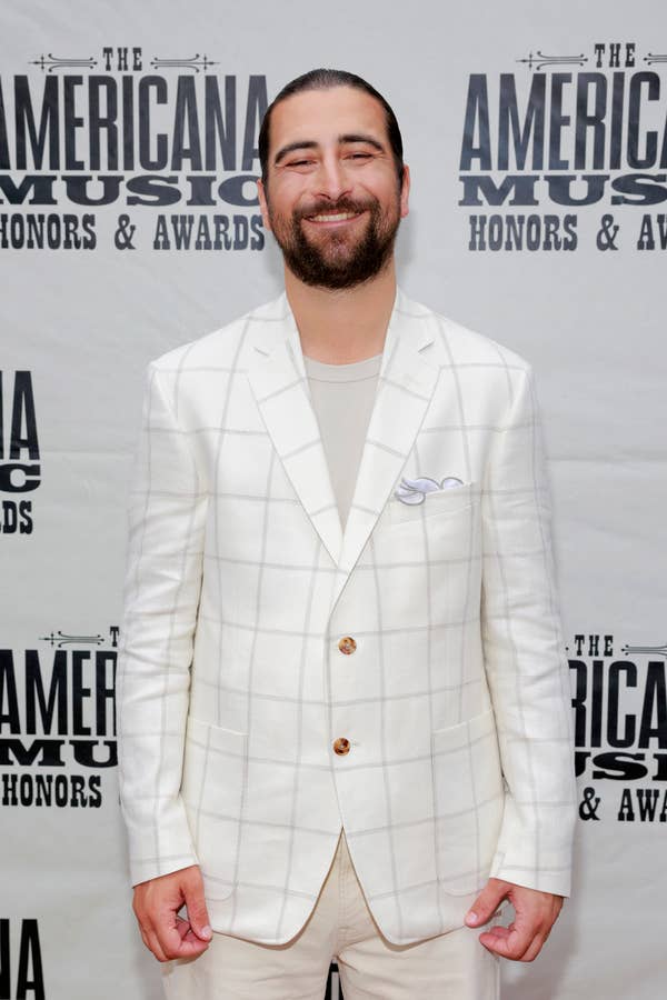 A man in a white plaid suit poses on the Americana Music Honors &amp;amp; Awards red carpet