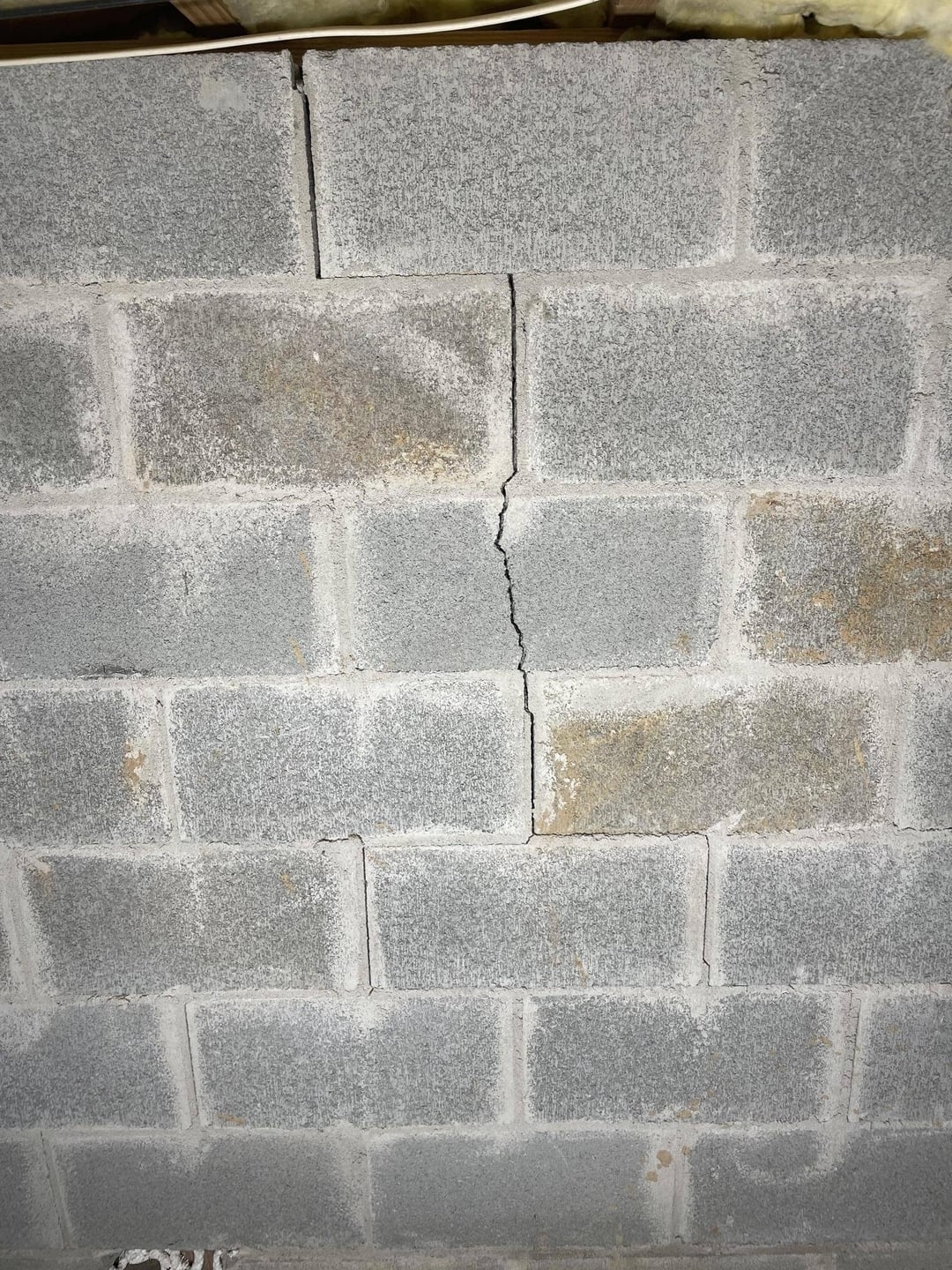 Cracked cement block wall with visible horizontal and vertical lines