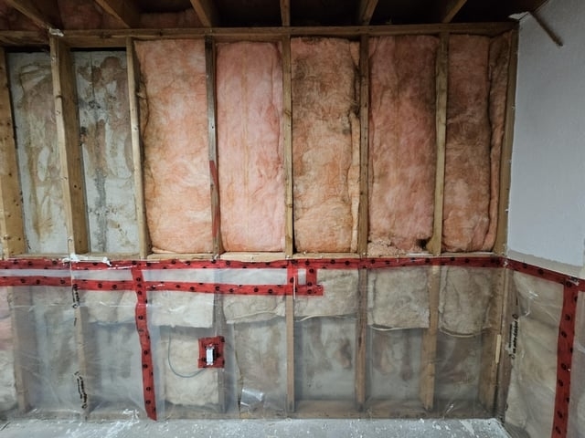 Exposed wall showing fiberglass insulation and electrical wiring in a home renovation project
