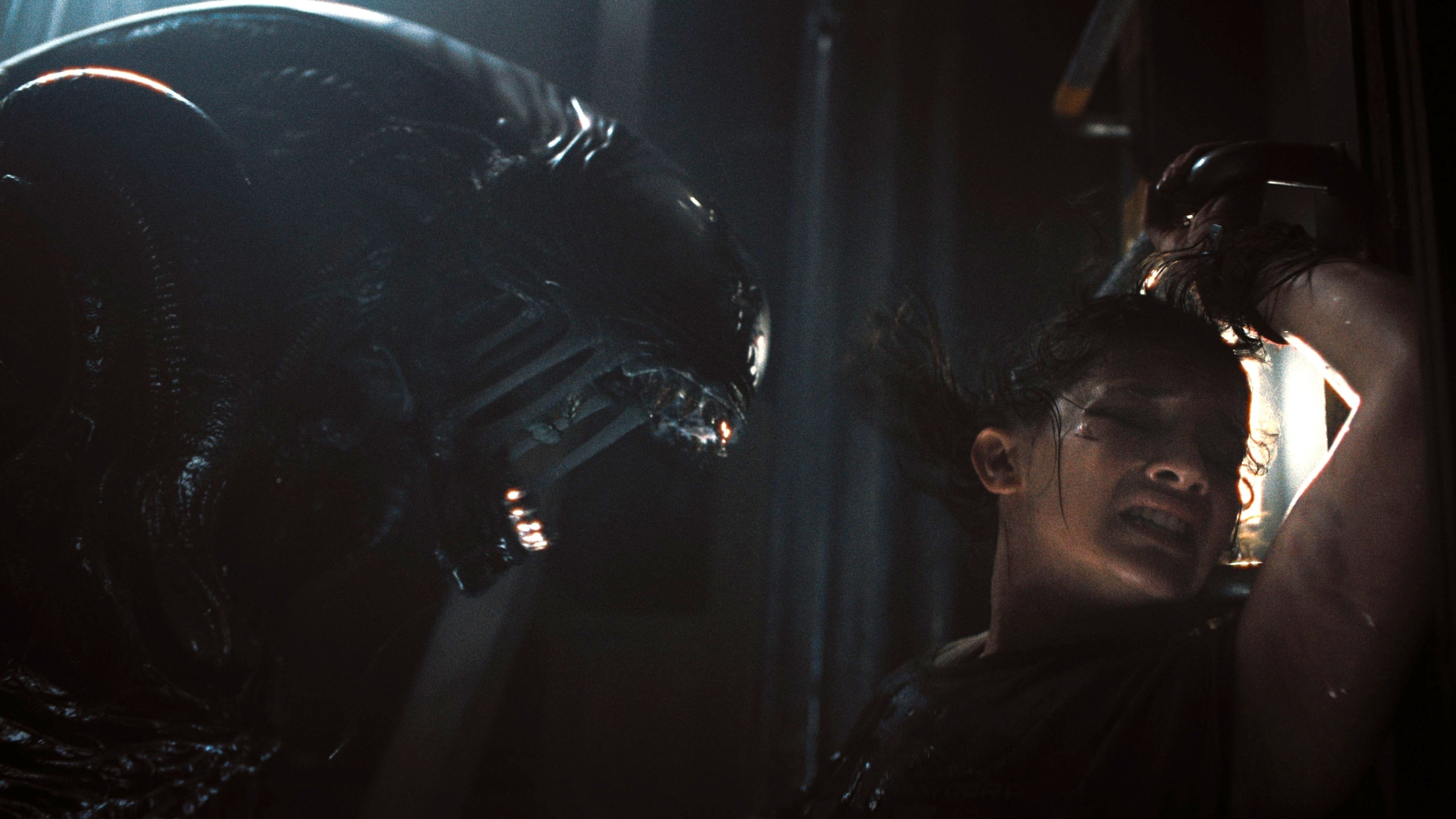 A person struggles against an alien creature in a dark, tense scene resembling a sci-fi movie