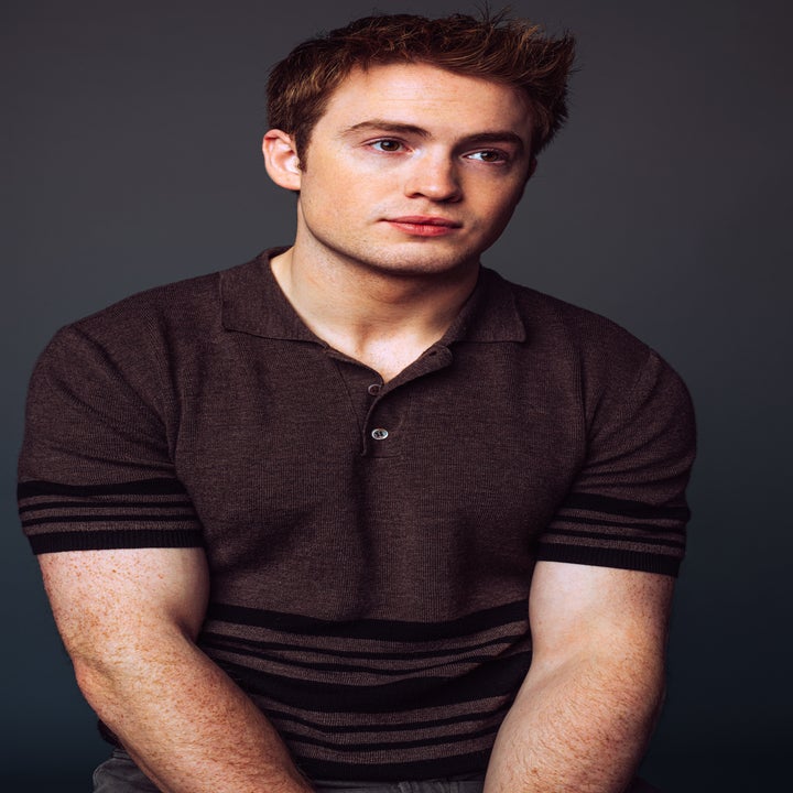 Kit Connor is seated, wearing a collared shirt with stripes