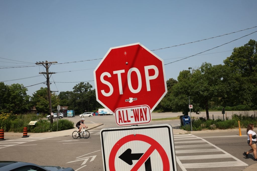 Stop sign with additional "All-Way" message at a street intersection; cyclist in the background