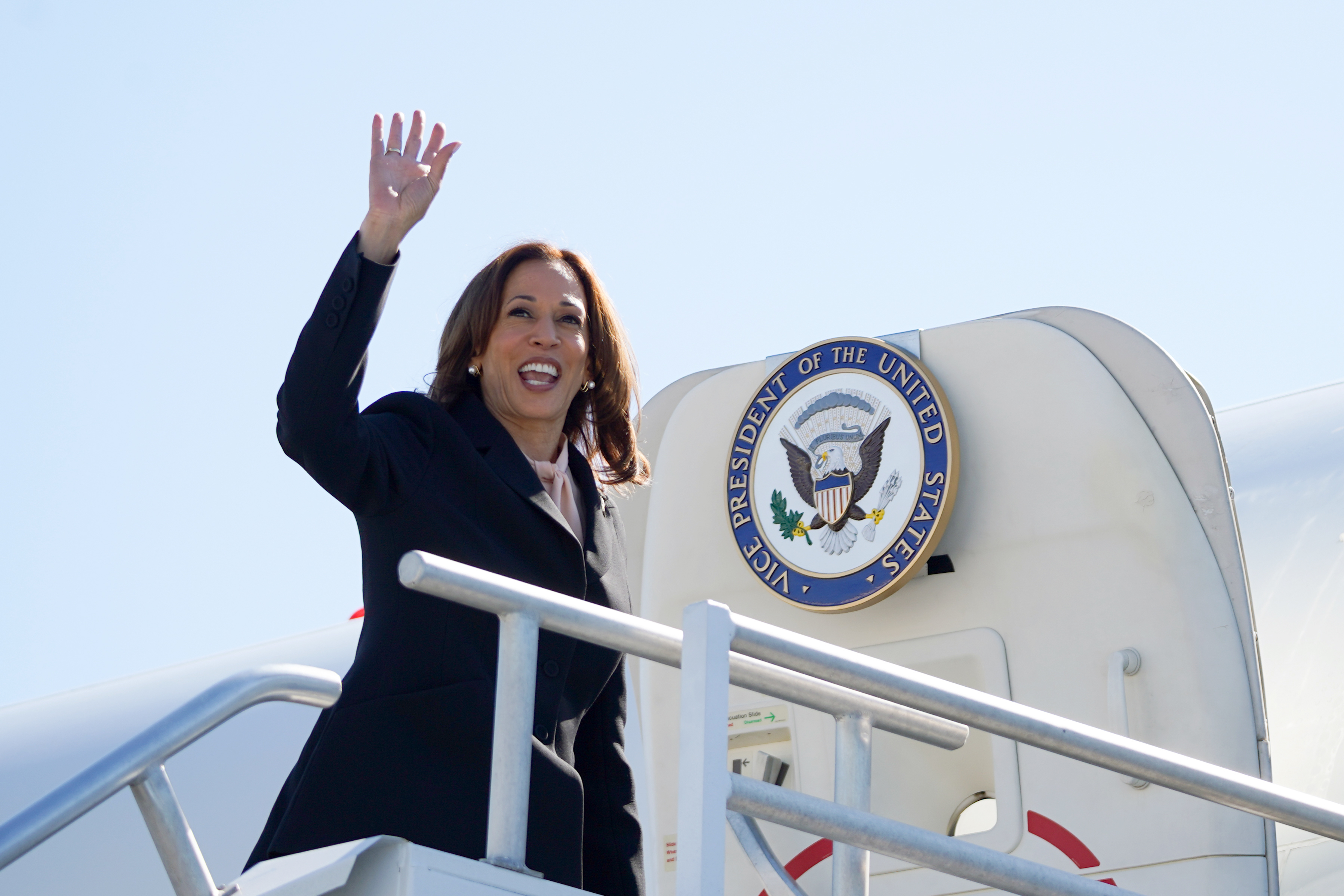 A person waves while boarding a plane with the Vice President seal visible near the door