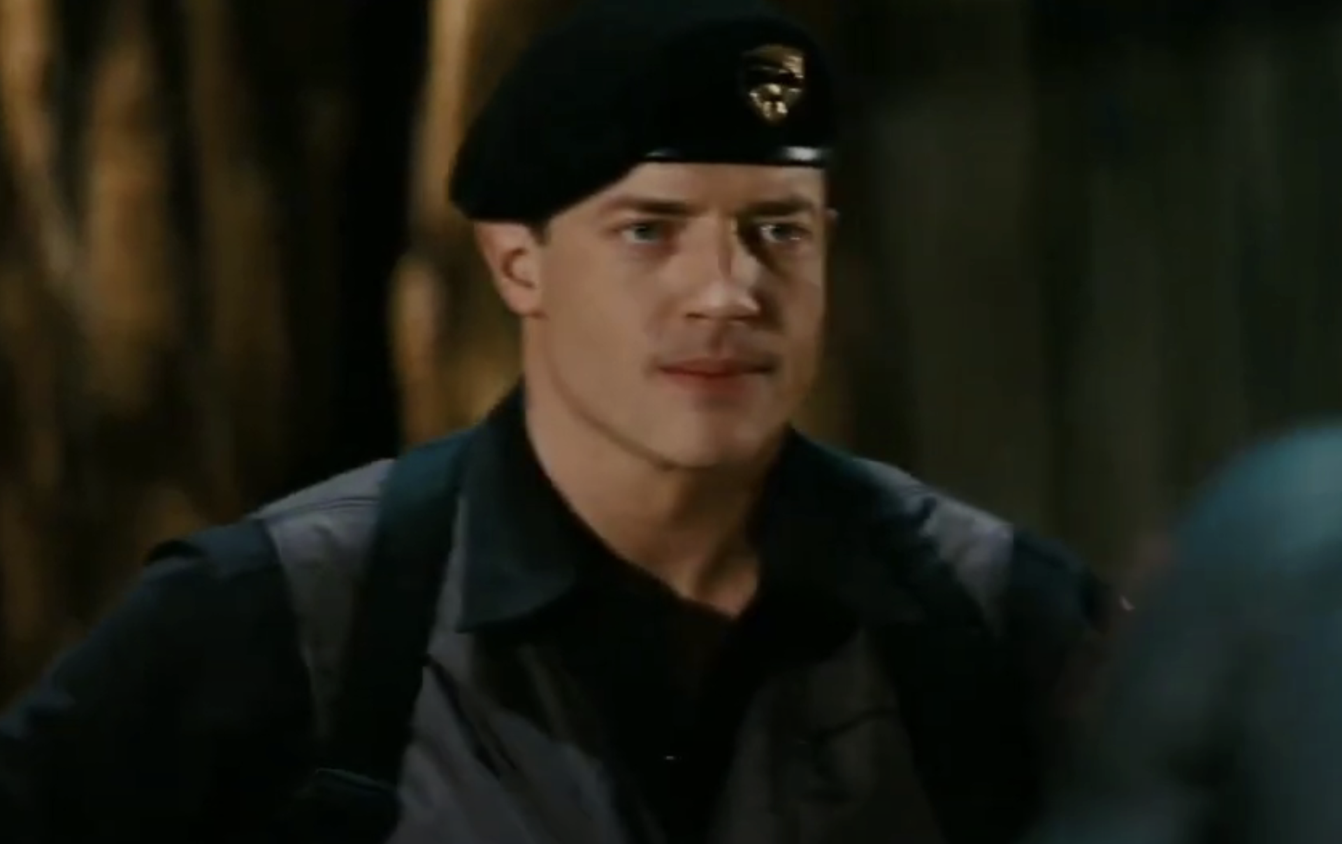 Brendan wearing a beret and uniform is in an outdoor setting, looking determined