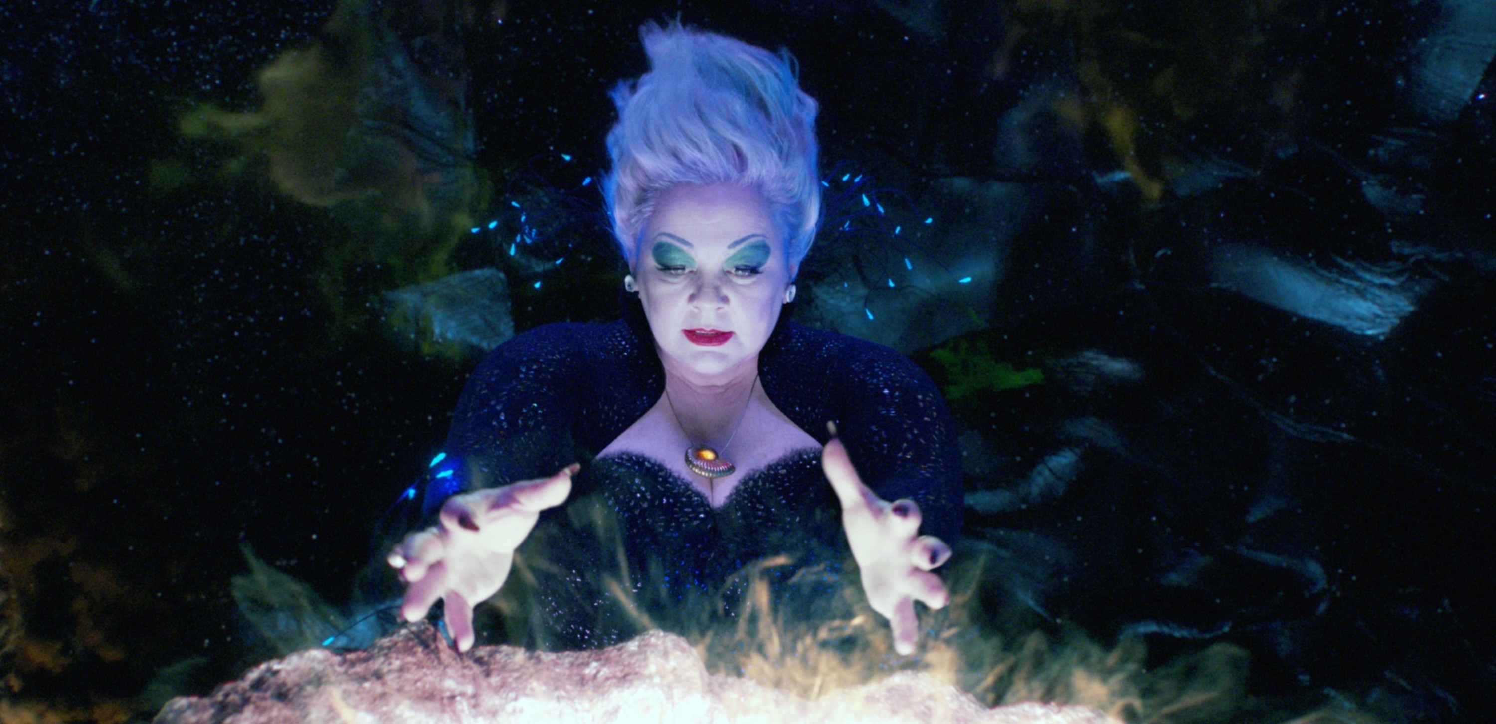 Ursula from "The Little Mermaid" with bright hair and dramatic eye makeup, casting a spell with glowing hands
