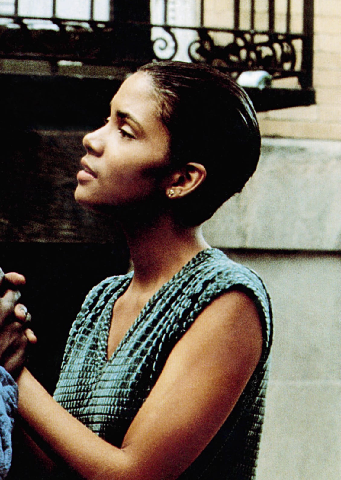 Halle with short hair and a sleeveless top, holding hands with a man in a scene