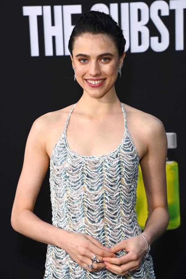 Margaret in a textured spaghetti strap dress and silver rings posing on the red carpet