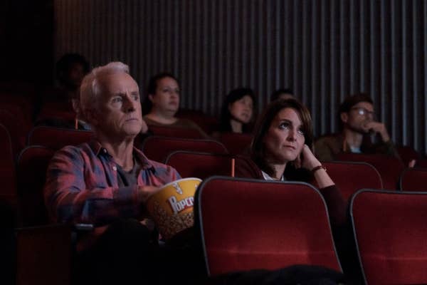 Audience members in a theater with popcorn, attentively watching a screen