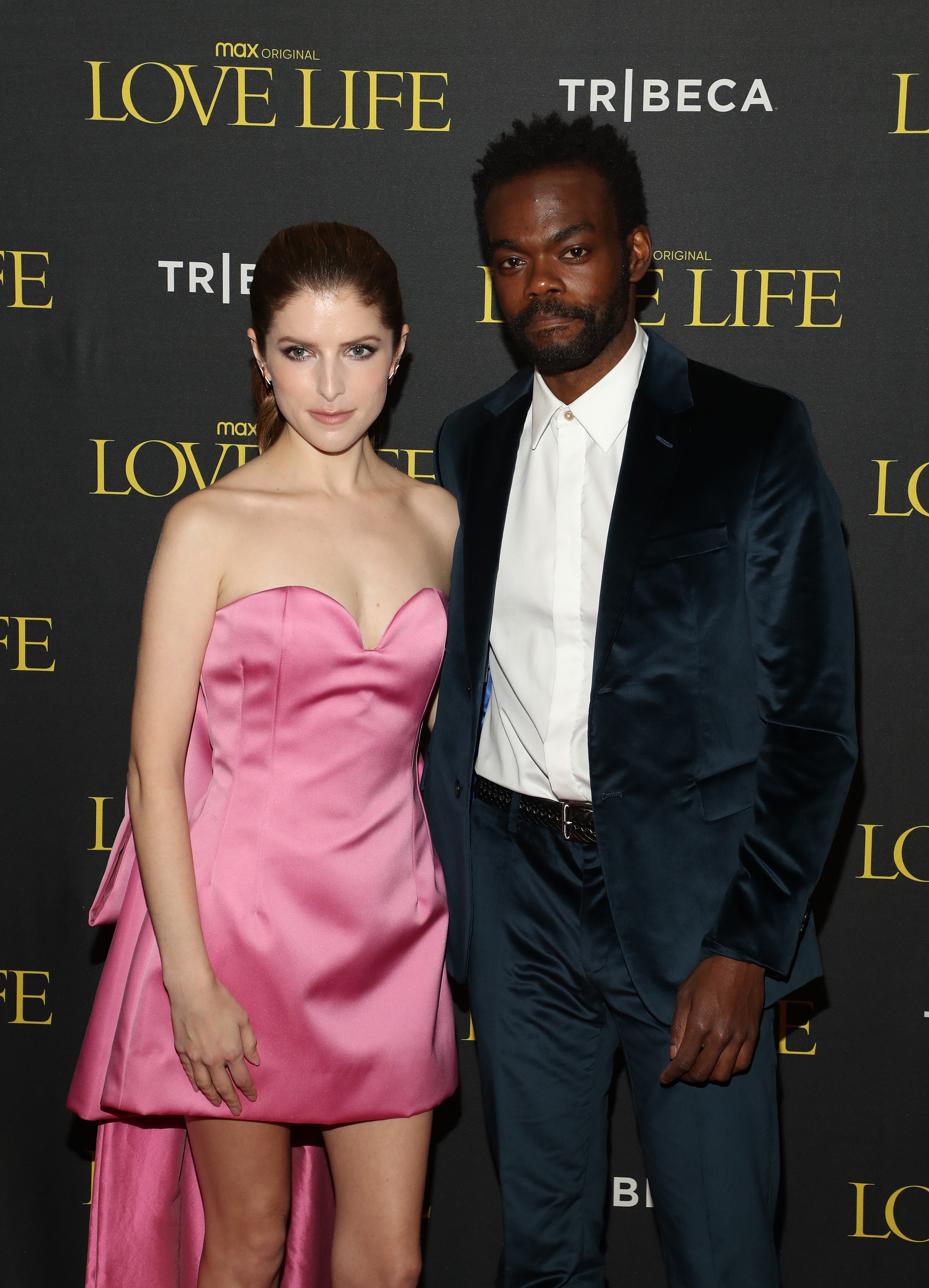 Two people at a "Love Life" event. The woman wears a strapless pink gown, and the man wears a dark suit