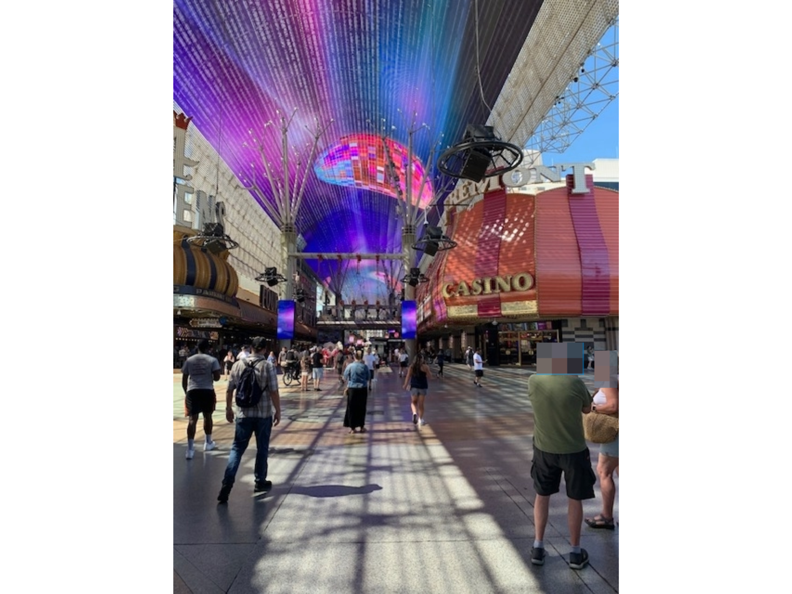 People walking under a lit canopy at Fremont Street, Las Vegas, surrounded by casinos and shops