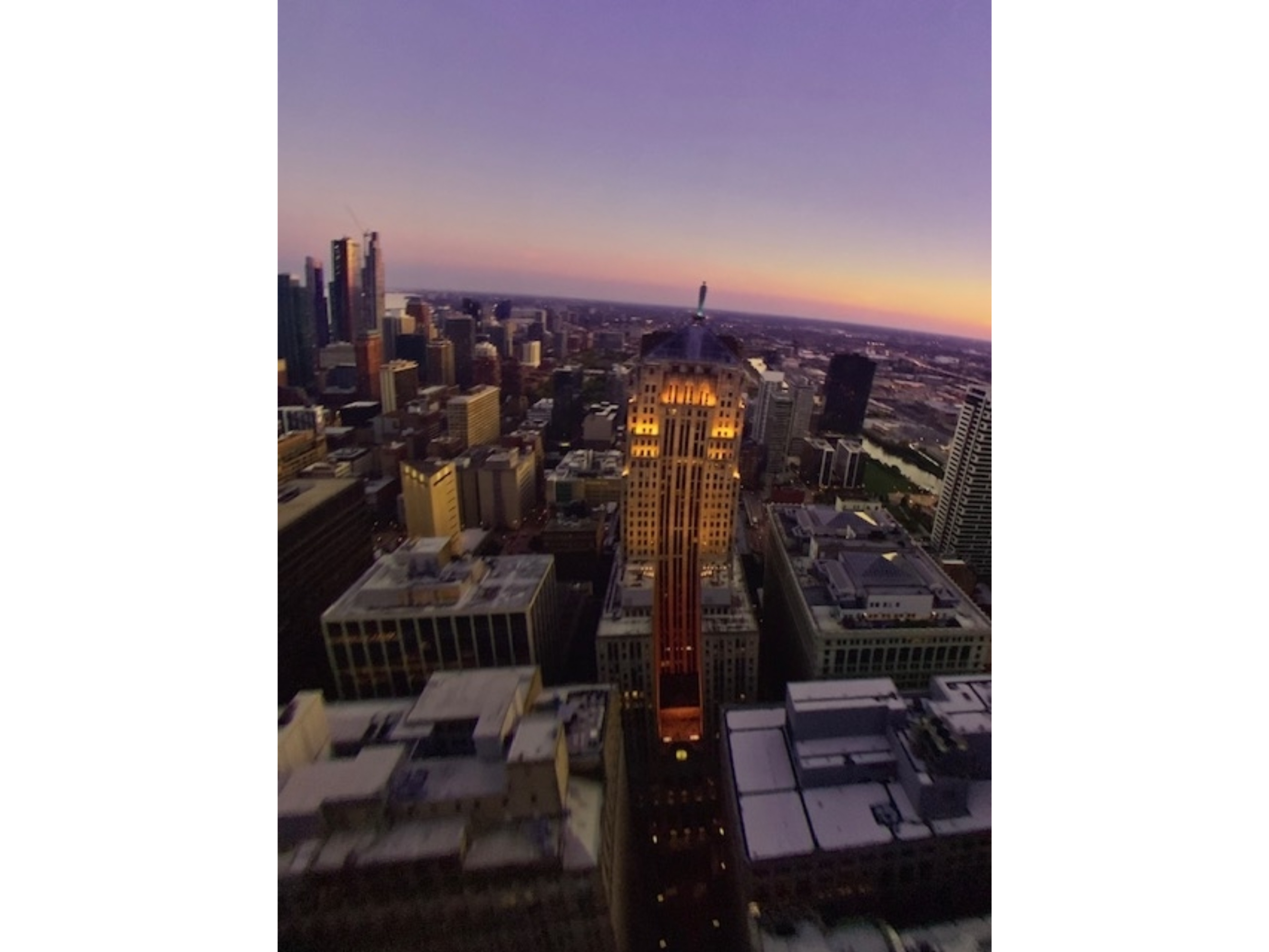 City skyline at dusk, with illuminated skyscrapers and horizon