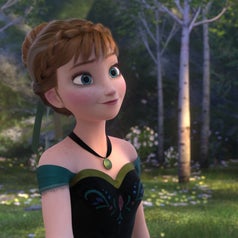 Anna from Frozen stands in a forest wearing a dress with floral patterns