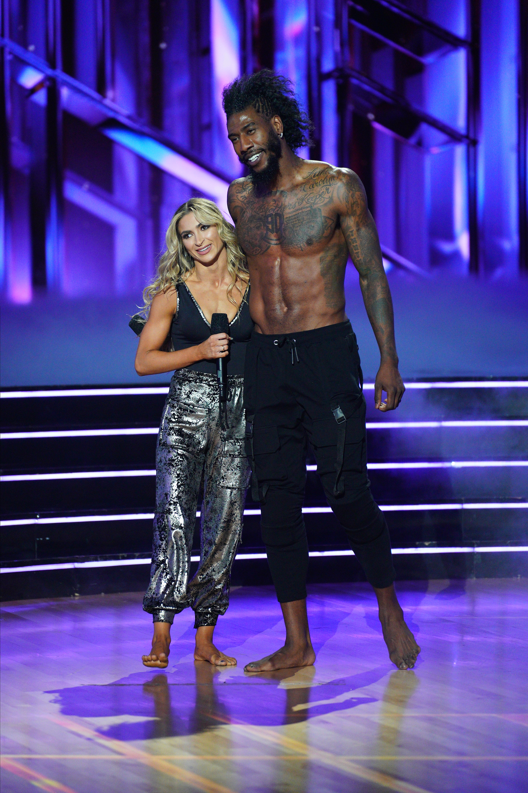 Iman Shumpert and Daniella Karagach on stage at Dancing with the Stars. The woman wears a glittery jumpsuit, and the man is shirtless wearing dark pants