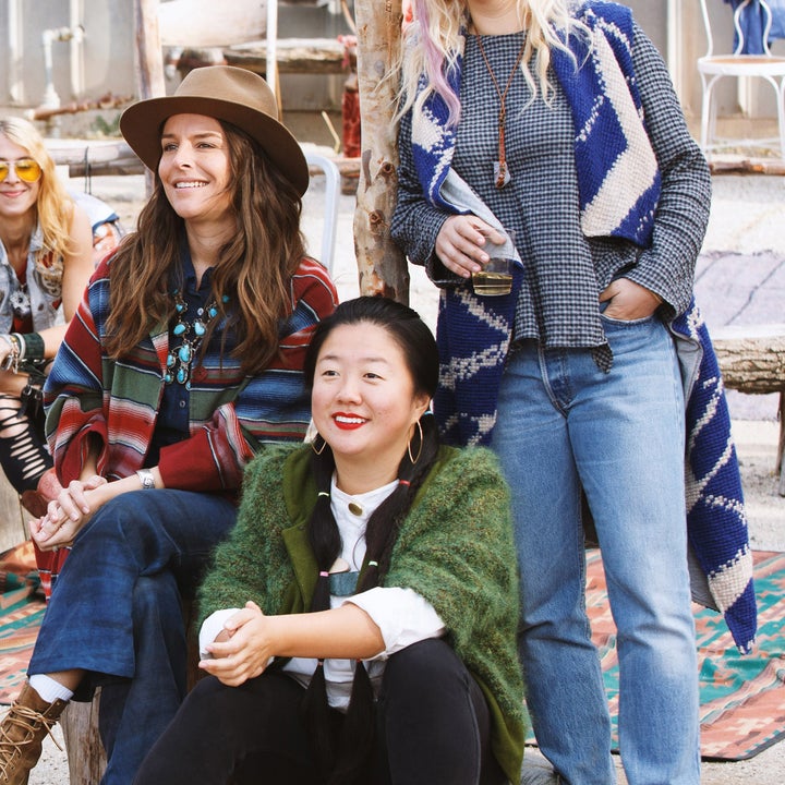 A group of people at an outdoor gathering. They are dressed in casual, colorful clothing, with a mix of patterns and styles