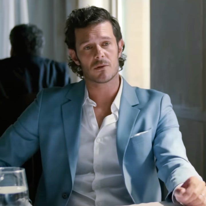a man in a blazer and white shirt talking to another man in a restaurant