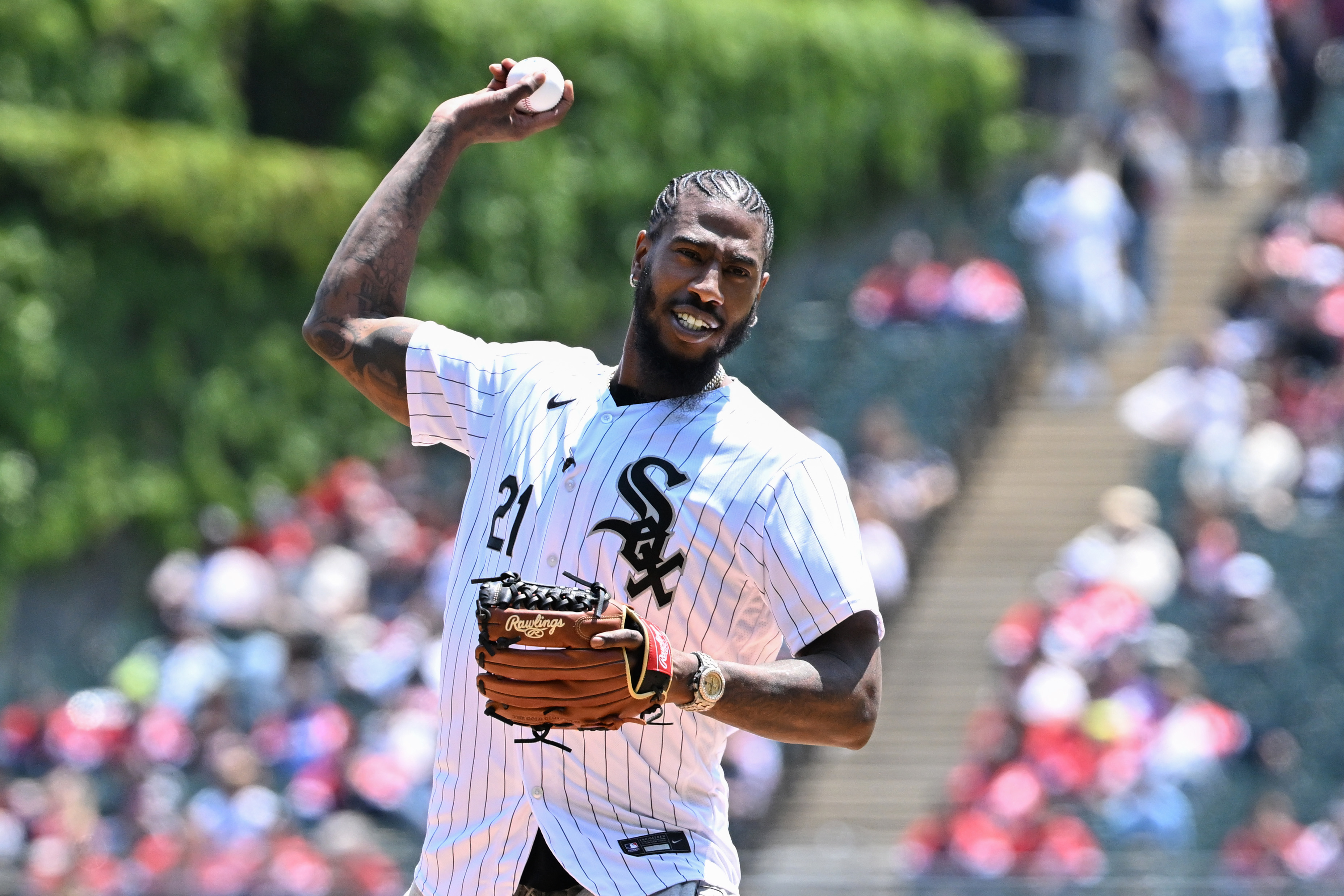 Iman Shumpert wearing a striped baseball jersey and throwing a pitch on a baseball field