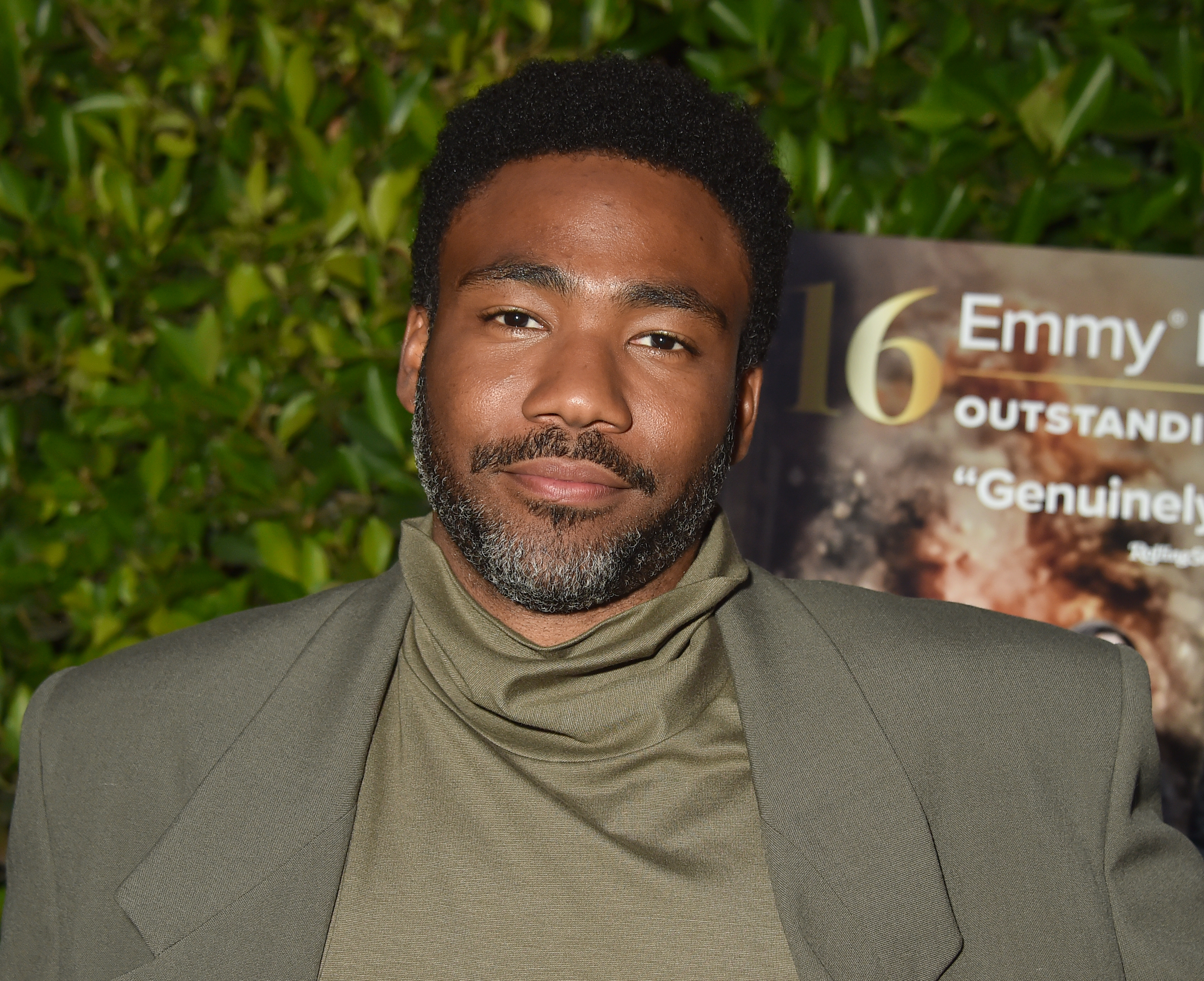 A person in a turtleneck and blazer attends a media event