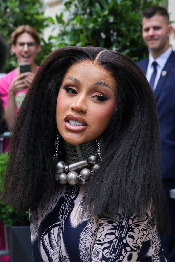 Cardi B leaving a hotel in a printed jacket with a giant necklace and slits through her eyebrows