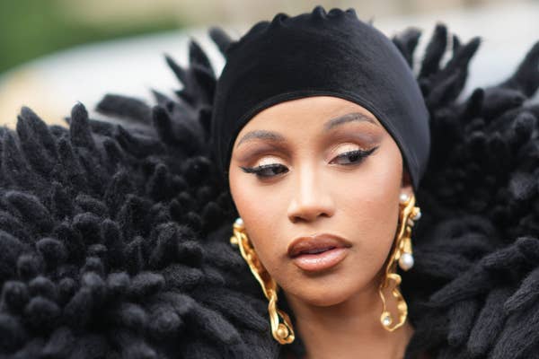 Cardi B in textured attire with a head scarf and bold drop earrings