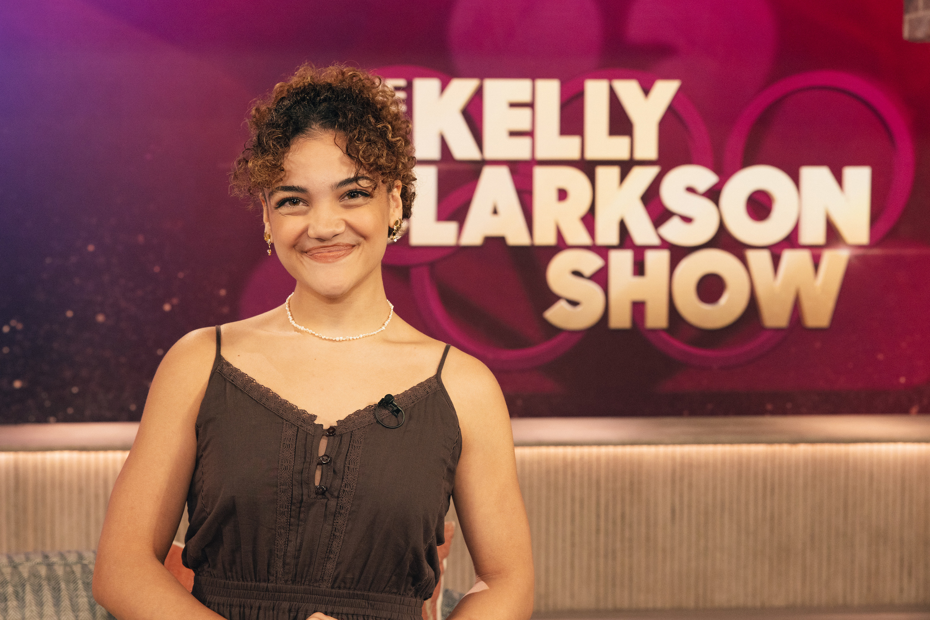 Laurie Hernandez smiling on the set of &quot;The Kelly Clarkson Show&quot; wearing a casual, sleeveless dress