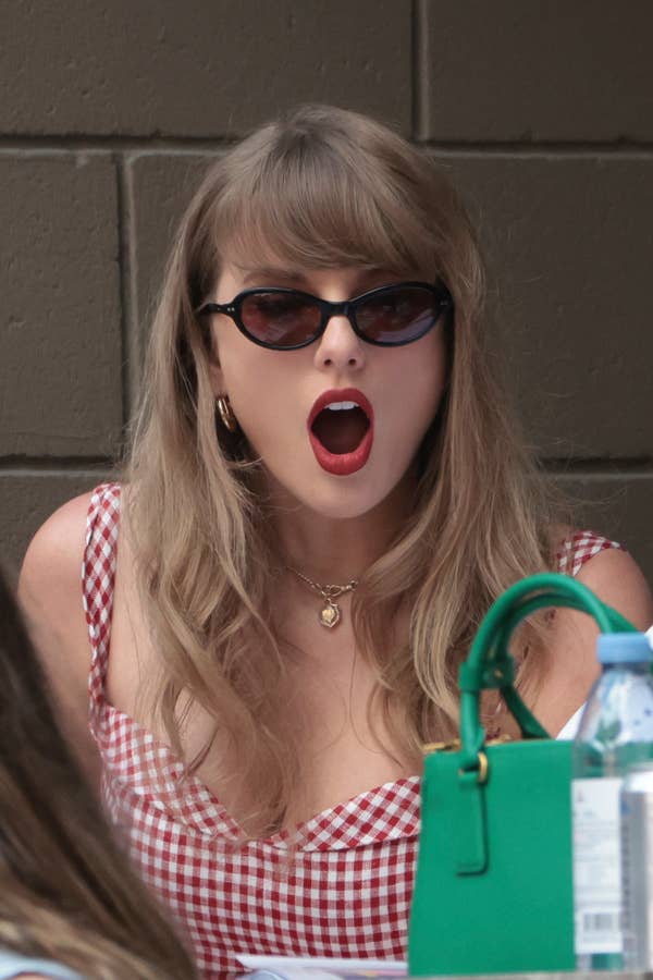 Taylor Swift wearing sunglasses and a checkered dress with an open mouth