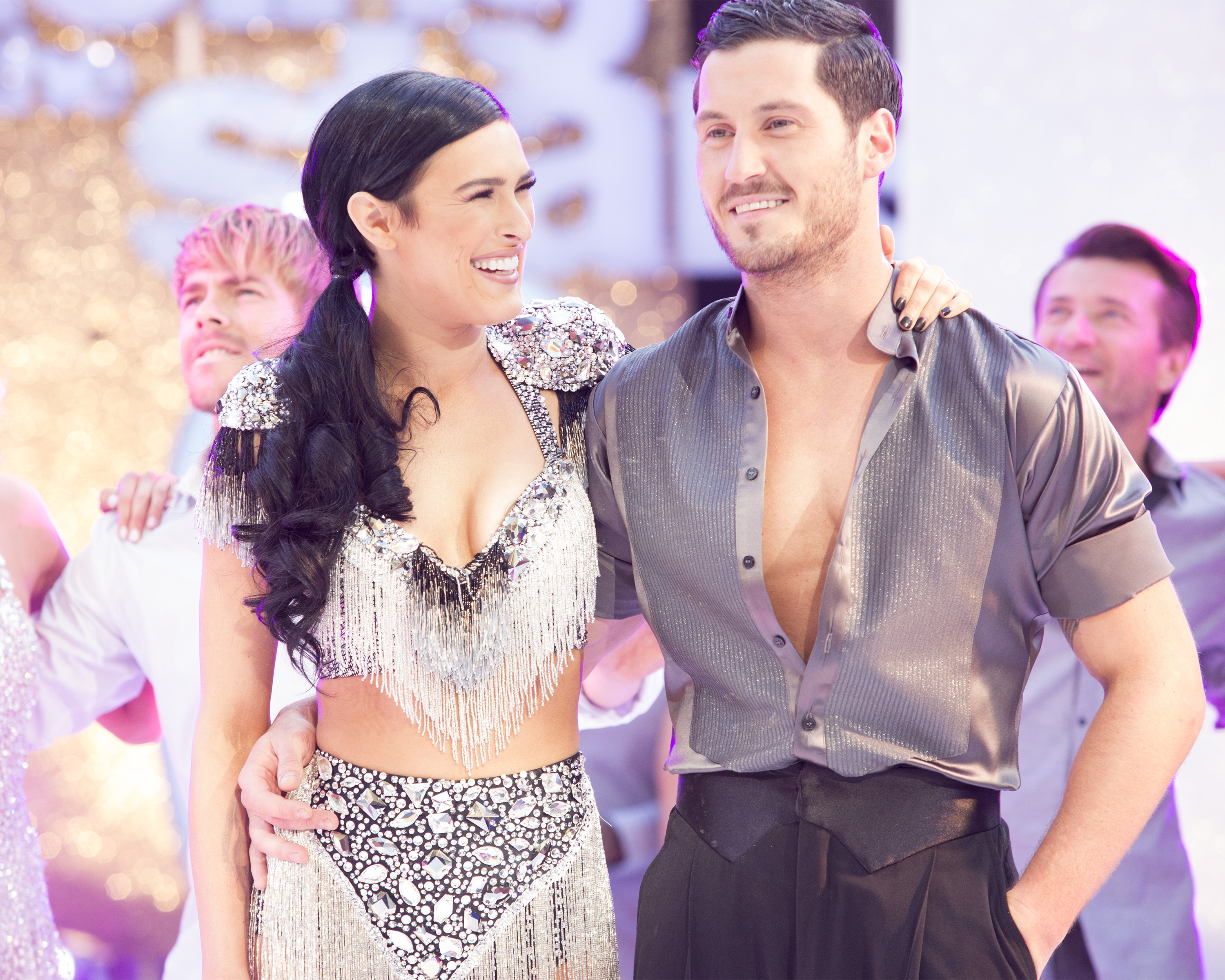 Rumer Willis wears a fringe outfit and Val Chmerkovskiy wears an open-neck shirt, and they embrace on Dancing with the Stars.A woman is wearing a fringe outfit with a sequin top, and a man is in an open-neck shirt