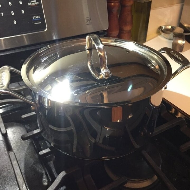 Shiny stainless steel pot with a lid sitting on a stove in a kitchen setting
