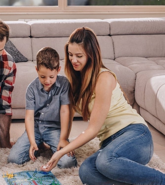 Family playing in living room; air purifier in foreground. Text highlights air cleaner&#x27;s ability to reduce pollution