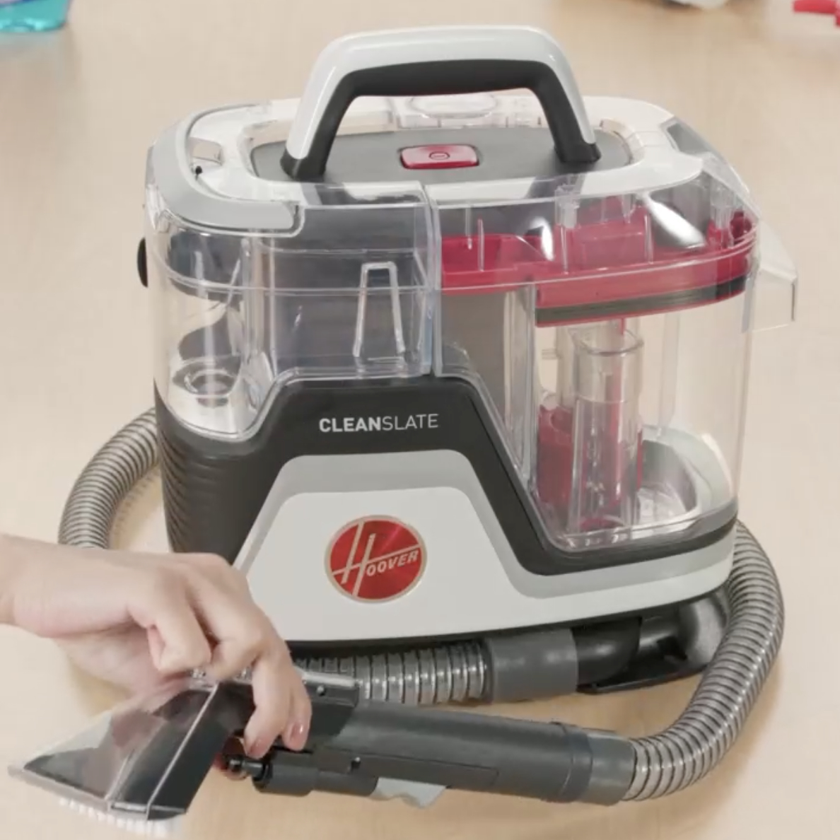 Hand holding the cleaning nozzle of a Hoover CleanSlate vacuum cleaner on a table