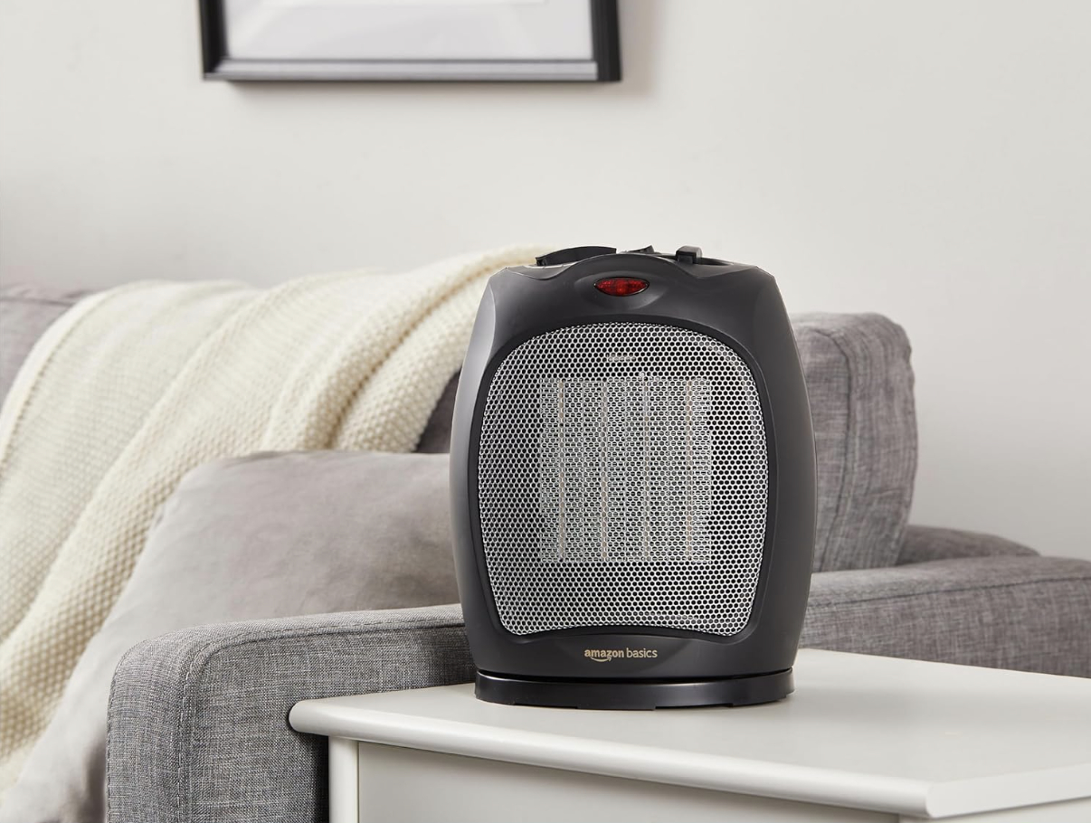 Small electric space heater on a living room side table, next to a gray sofa draped with a knitted blanket