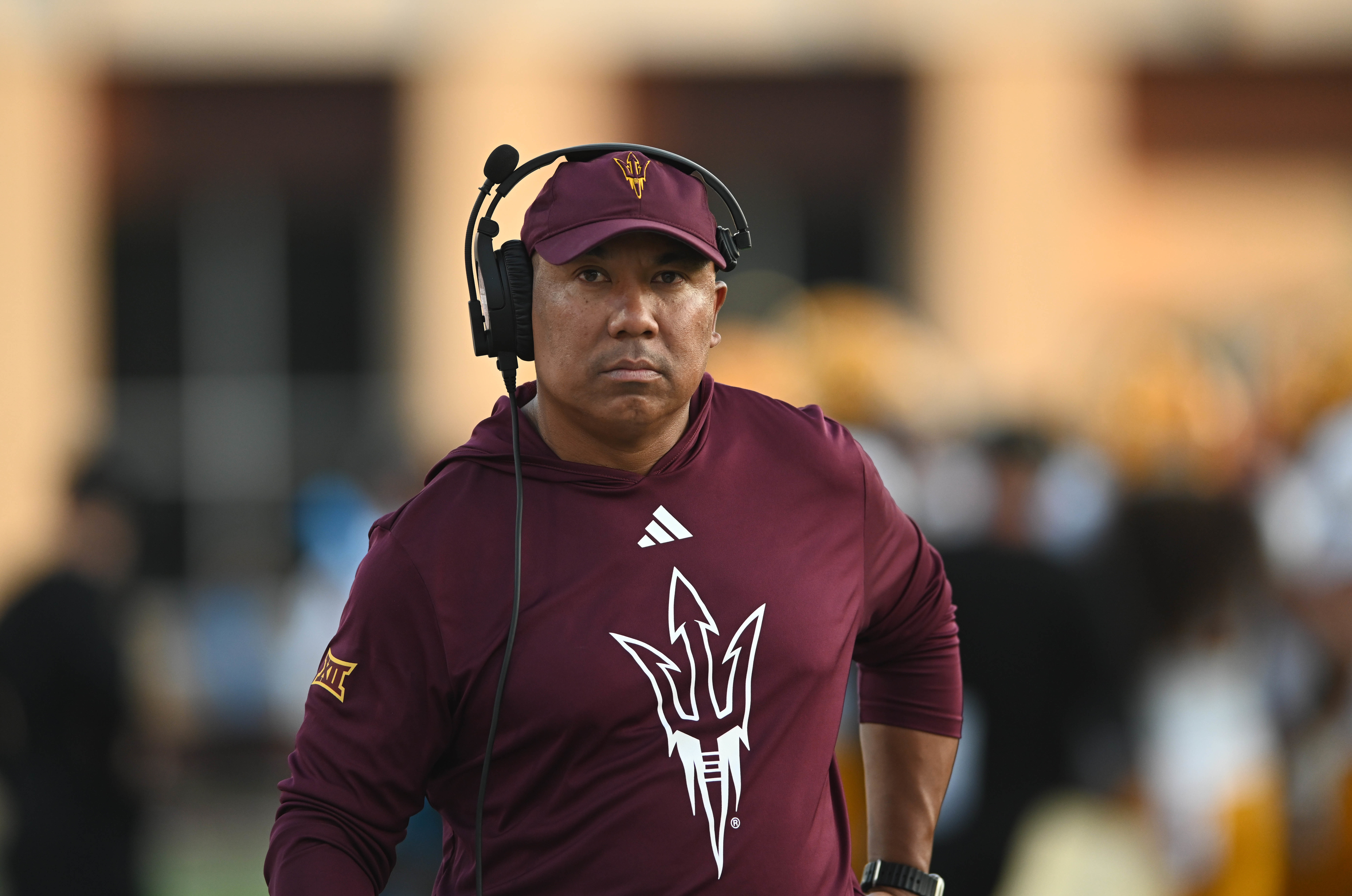 Hines Ward in a maroon Arizona State sports outfit with a logo and headset on a field, appearing focused