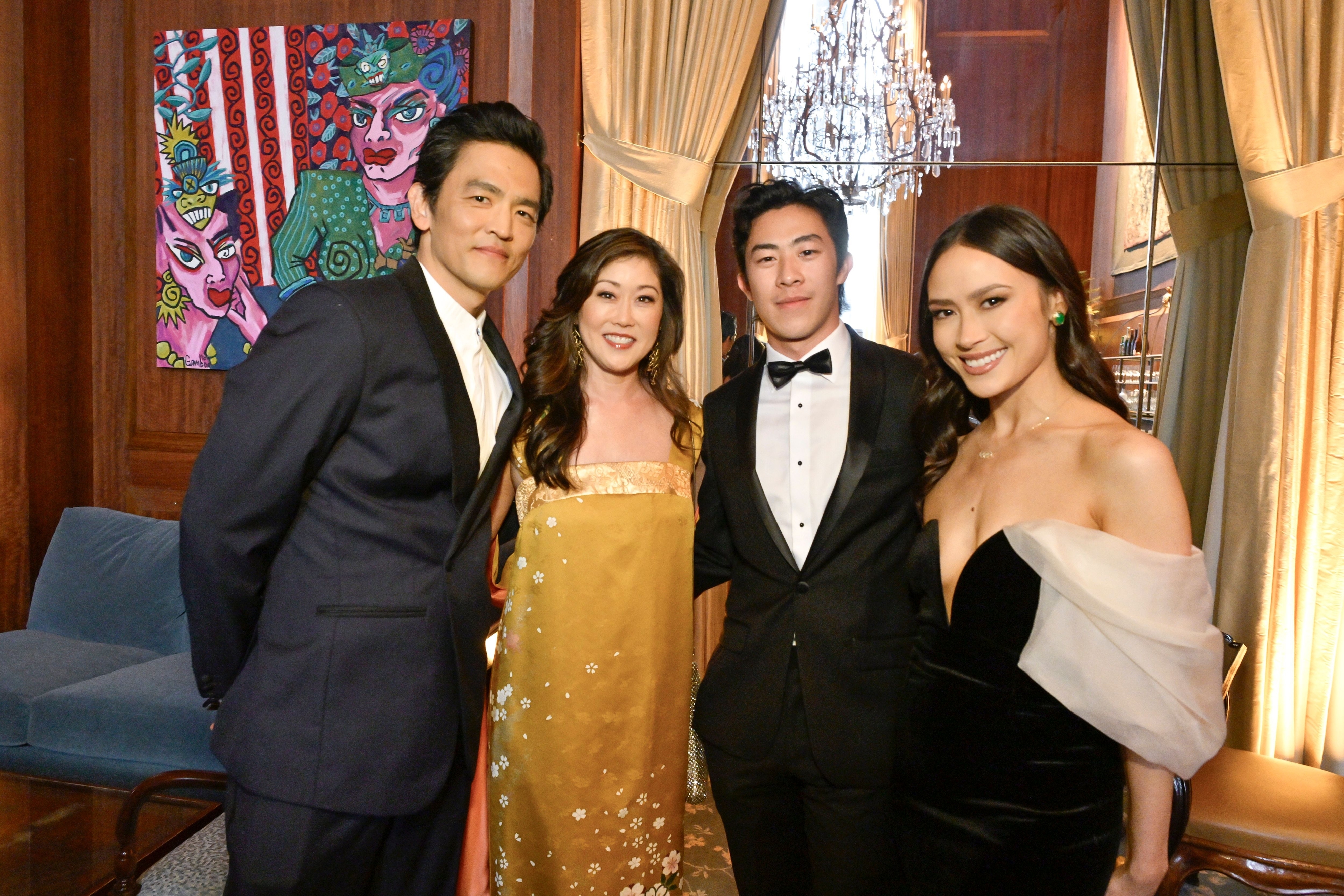 Four people in formal wear posing for a photo at an indoor event