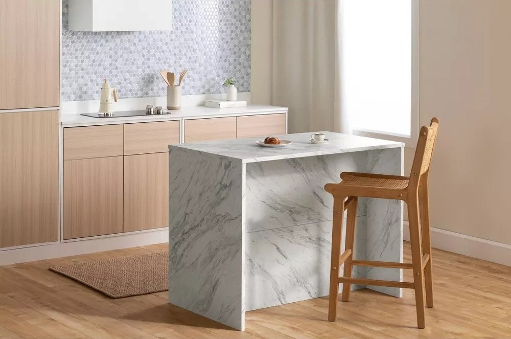 Modern kitchen with marble island, wooden cabinets, high wooden chair, and countertop accessories. Ideal for stylish home shopping