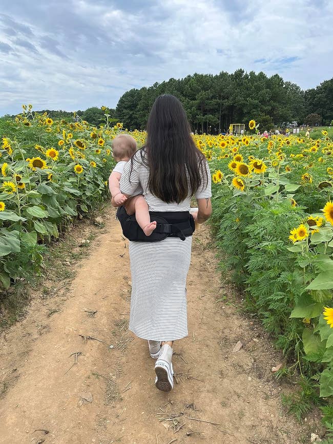 parent successful a striped formal carrying a babe successful a sunflower field