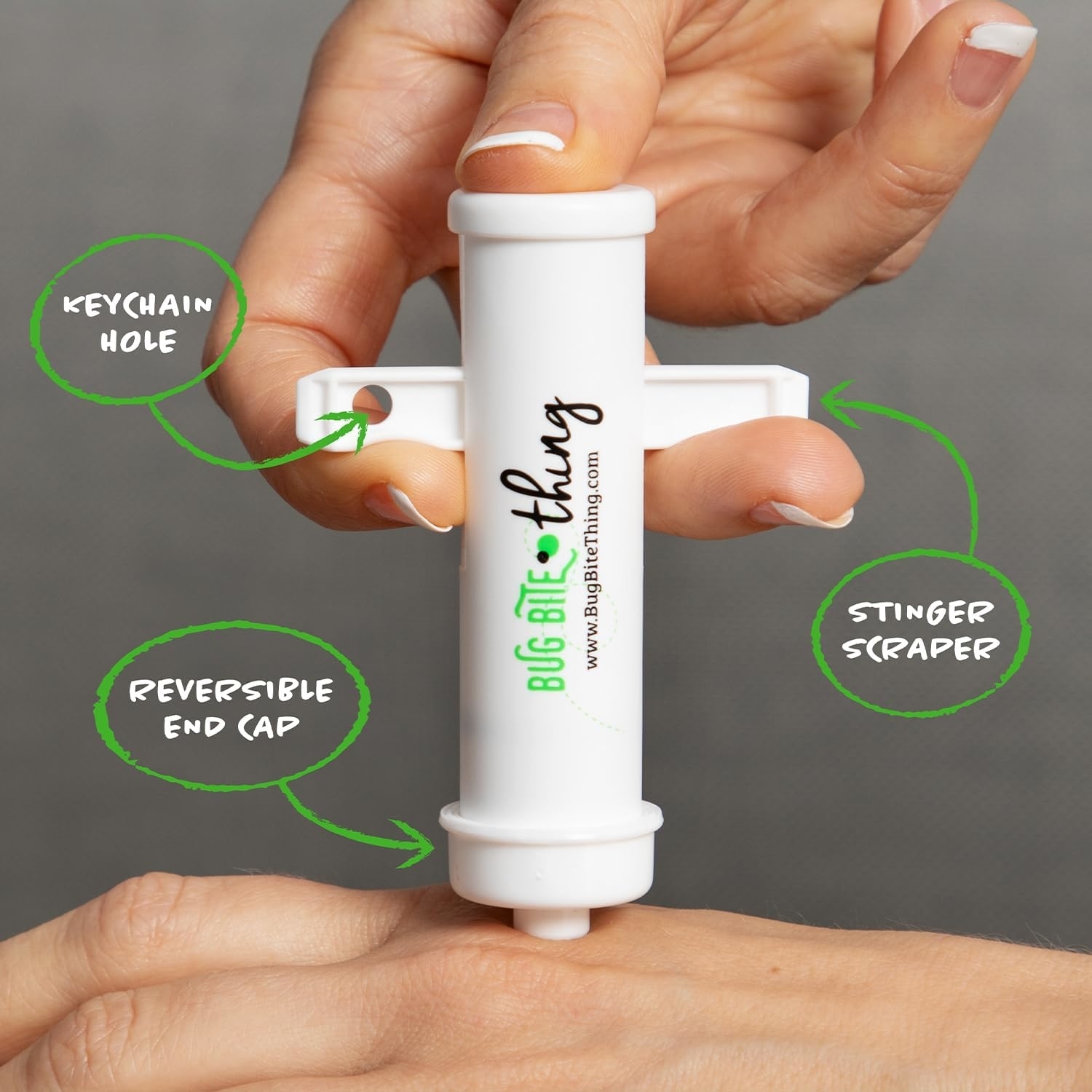 Device for bug bite relief with keychain hole, reversible end cap, and stinger scraper shown in use on a person&#x27;s hand