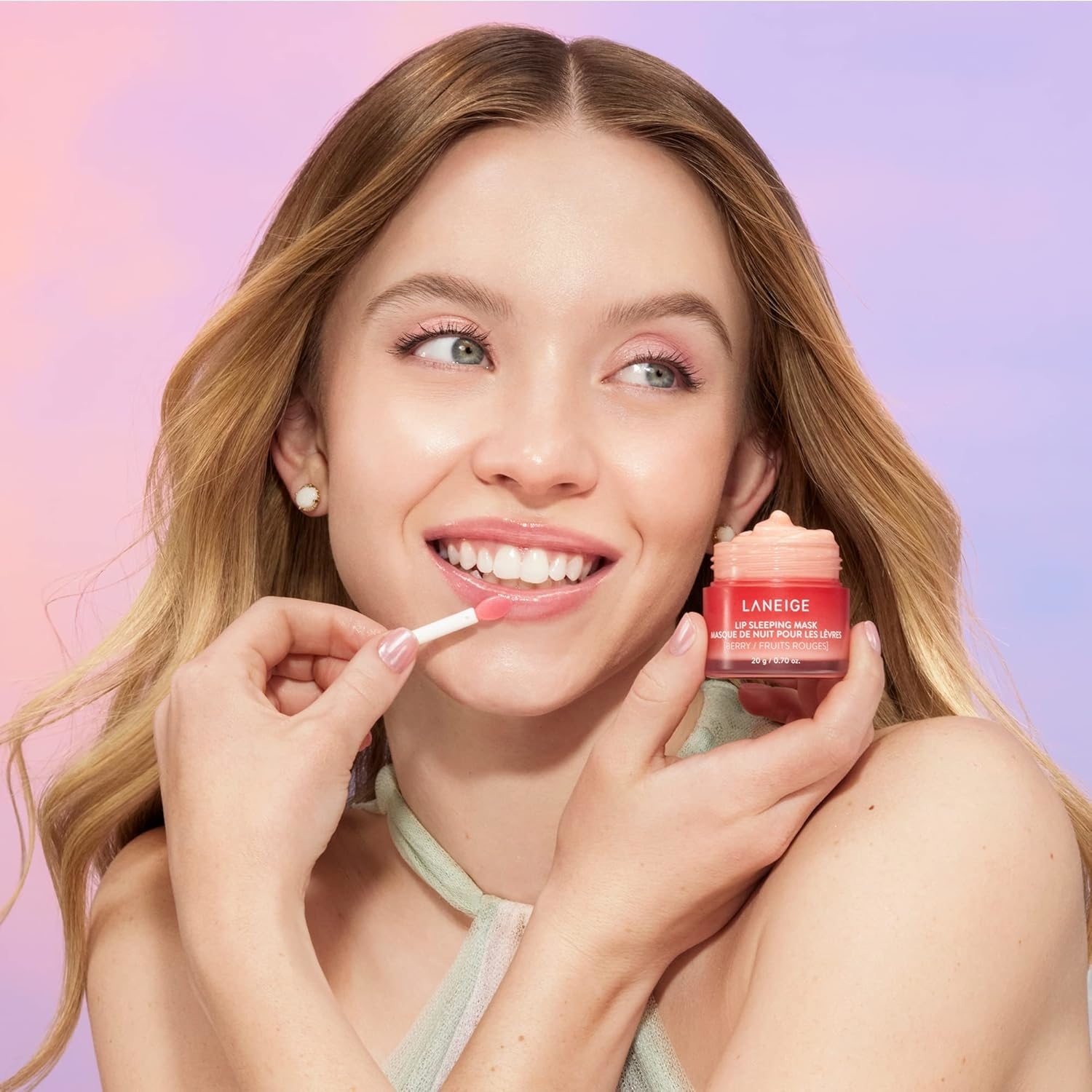 Model applying lip balm from a Laneige container, smiling