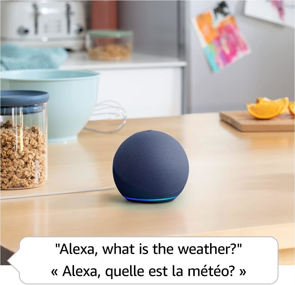 A smart speaker is in a kitchen setting. The text bubble says, &quot;Alexa, what is the weather?&quot; in English and French