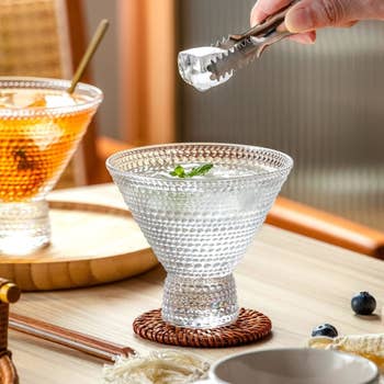 Person utilizing tongs to spot crystal successful a textured solid connected a table; different portion with crystal and garnish is nearby. Various tiny items and nutrient are visible