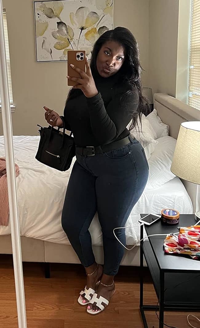 Reviewer successful a chamber reflector selfie wearing a achromatic top, faux leather leggings, and achromatic sandals, holding a achromatic bag.