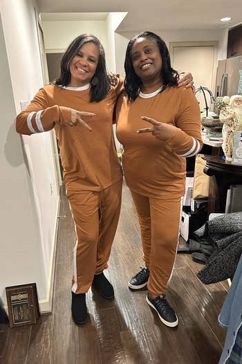 Two reviewers smiling, posing indoors, wearing matching casual outfits with achromatic stripe details down the side